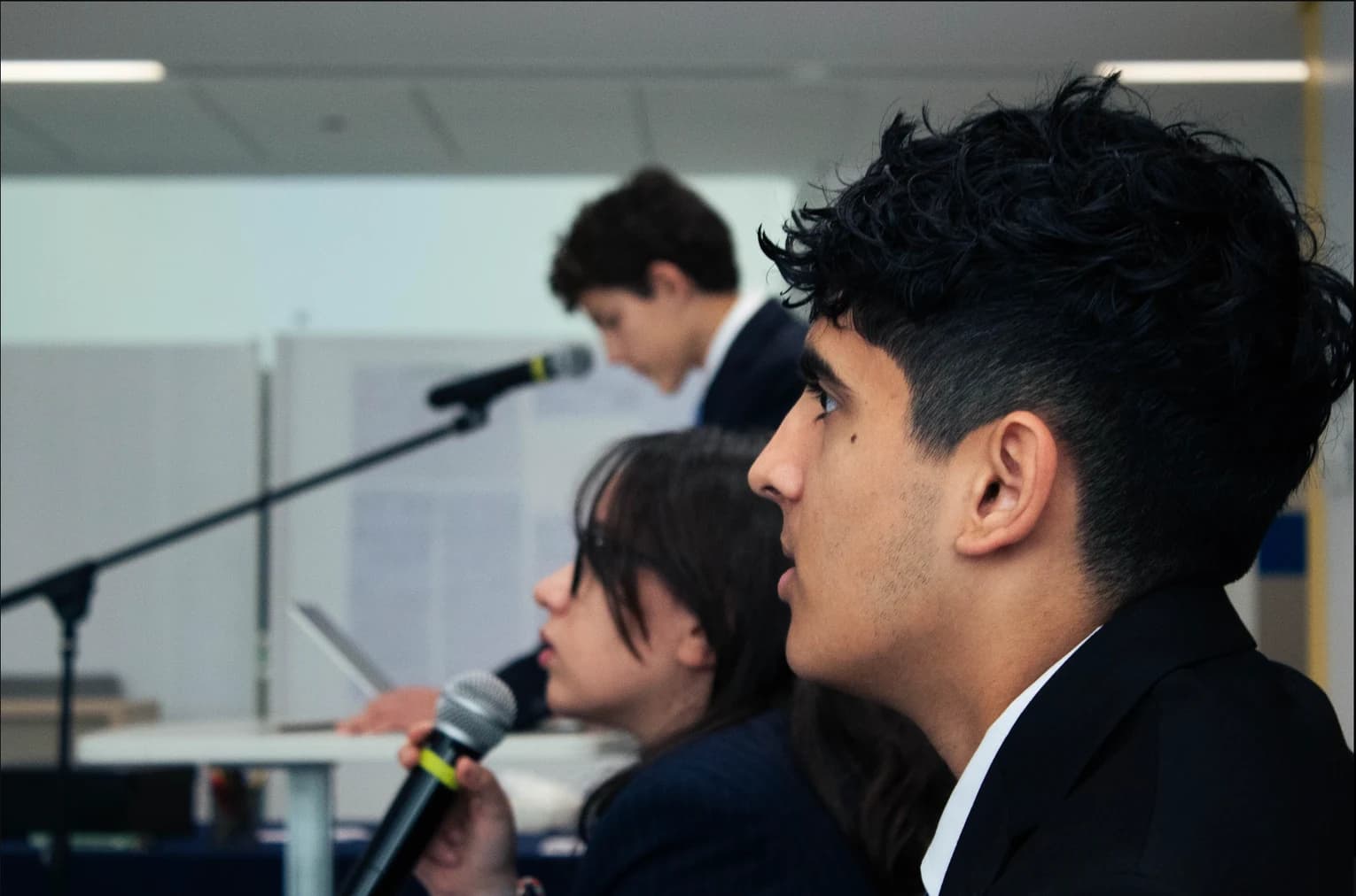 Three DHAMUN participants during a discussion, with a delegate in focus in the foreground