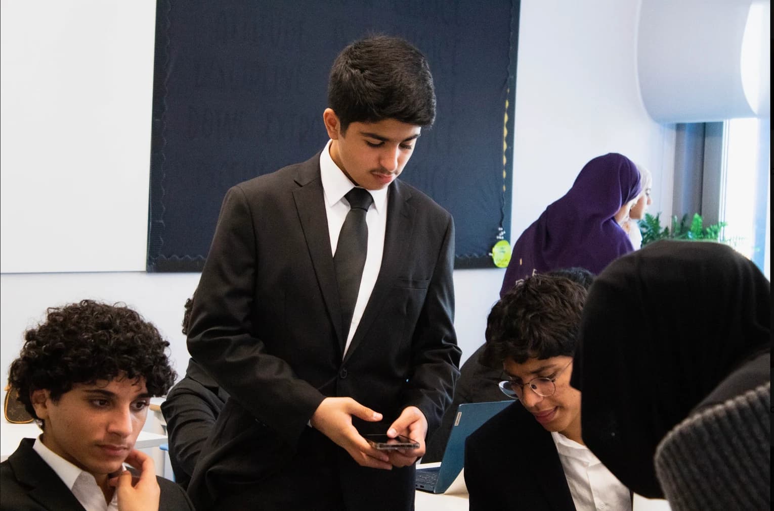 A DHAMUN participant checking a phone alongside fellow delegates