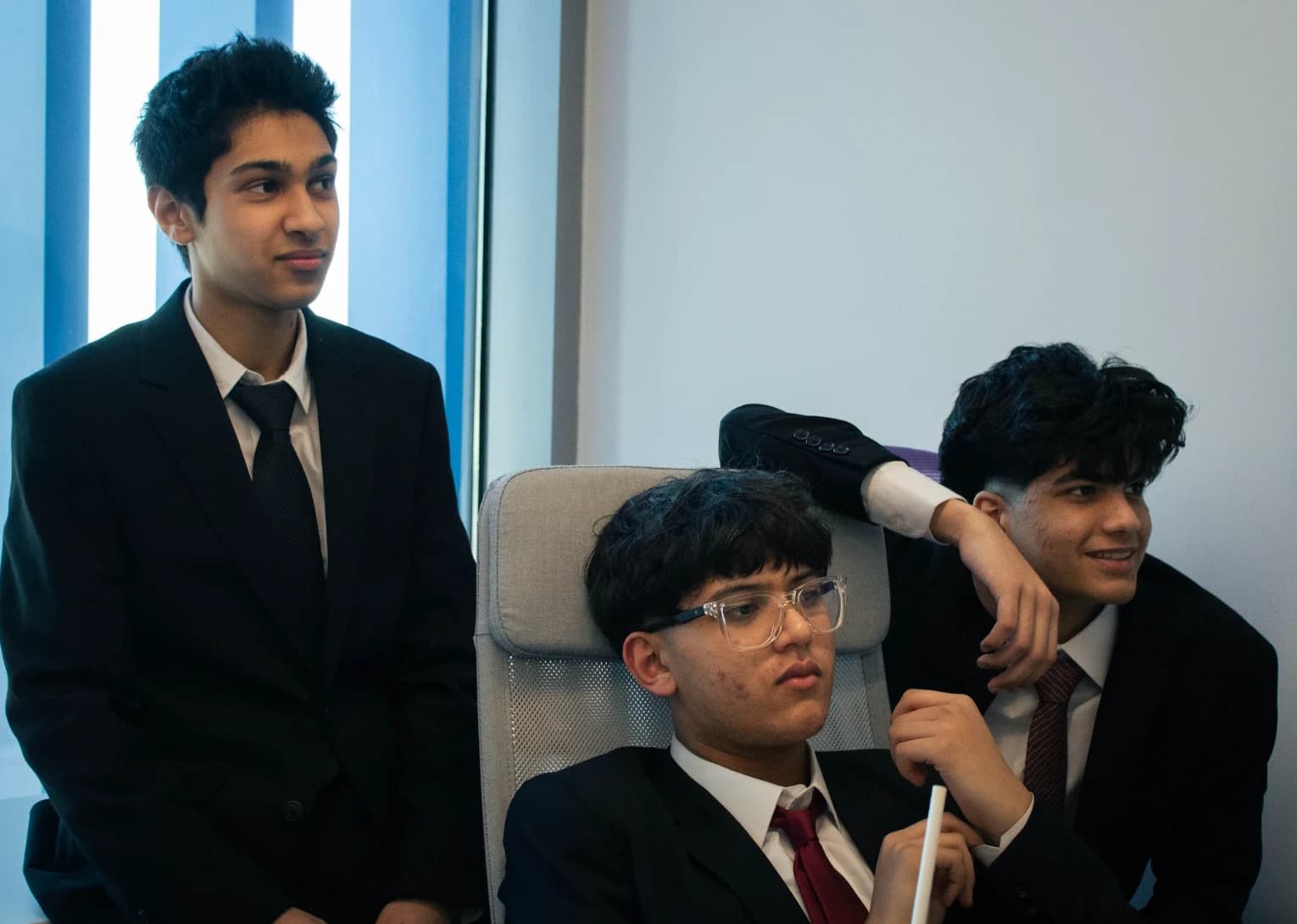 Three DHAMUN participants in suits sharing a moment between sessions